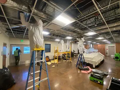 Crew in protective suits opening wet ceilings during a large water damage job