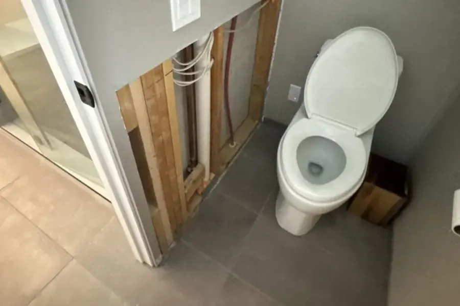 Bathroom wall opened beside a toilet so the cavity can dry